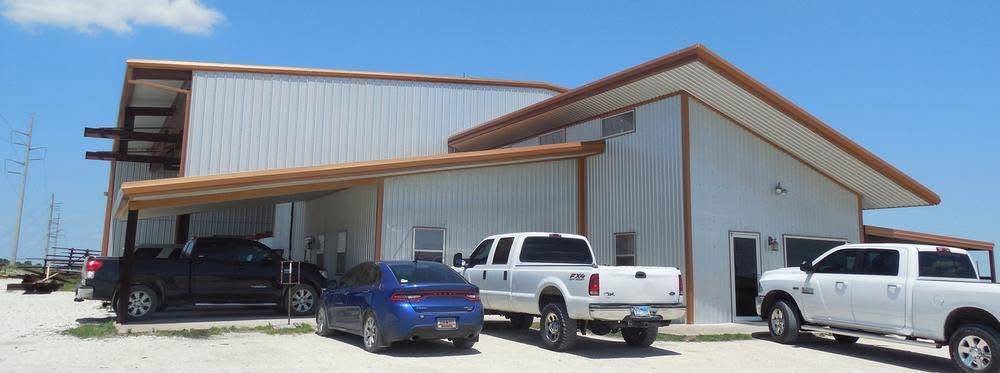 Tan metal building with orange trim and covered carport delivered by Brazos Metal Building Systems