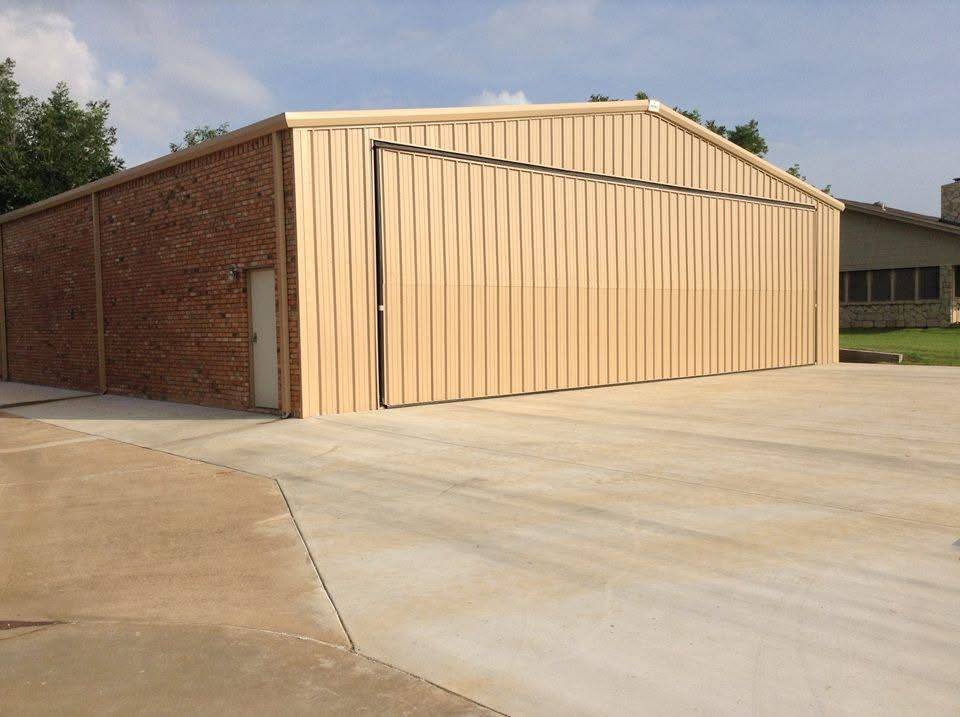 Tan metal hangar with brick wainscot and large sliding door for aircraft access