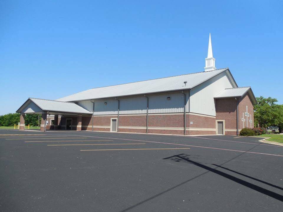 Brick and steel church building with white steeple and covered drop-off canopy